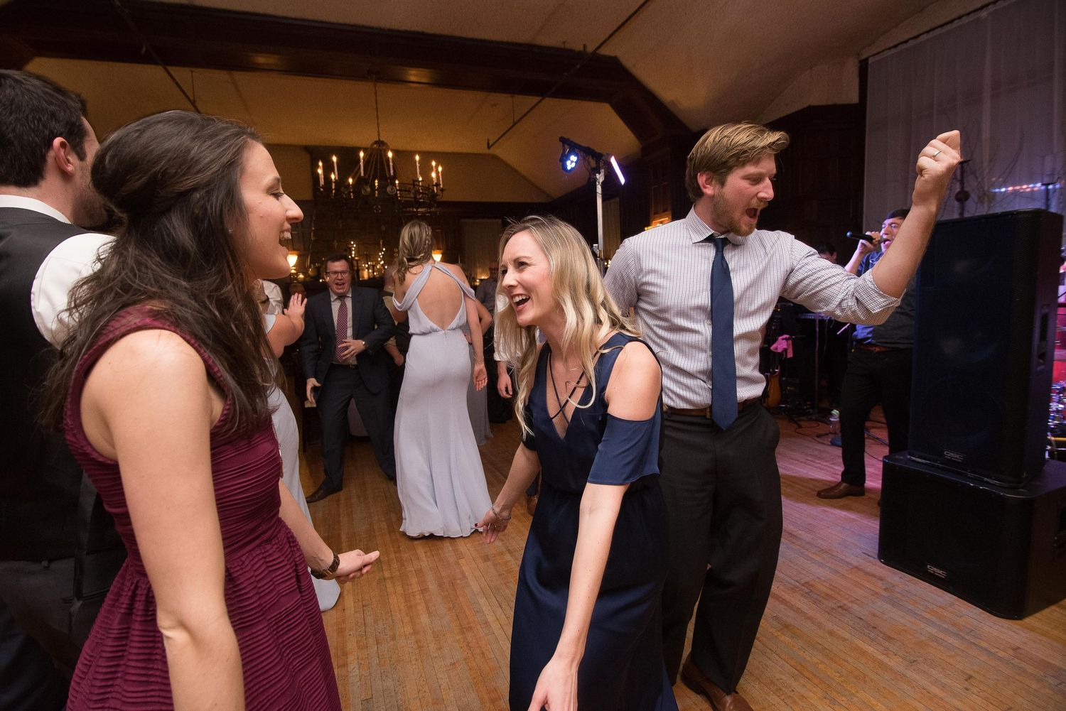Guests laughing and dancing together at an elegant indoor wedding reception party.