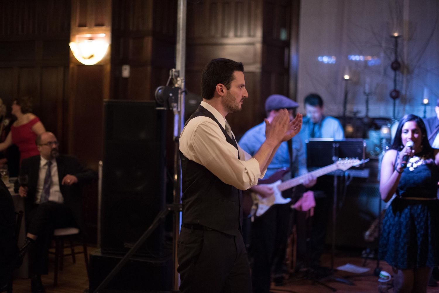 Male singer performing on stage with live band at elegant indoor event venue.