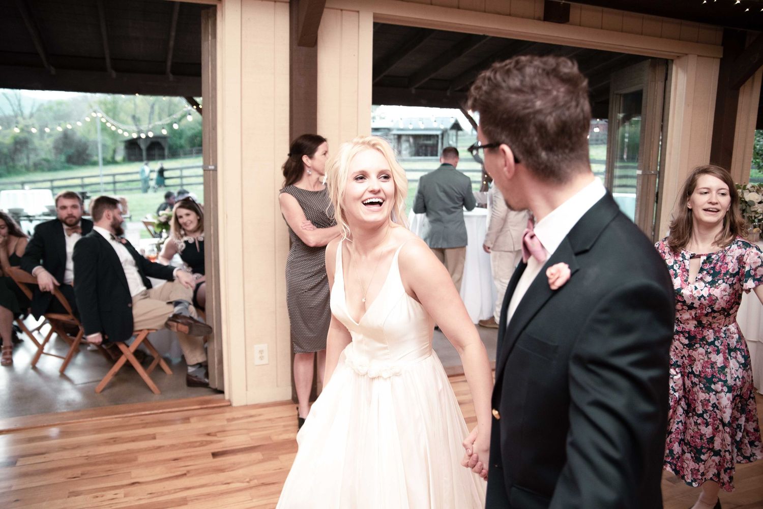 Bride and groom share a joyful first dance at elegant indoor wedding reception with guests watching.