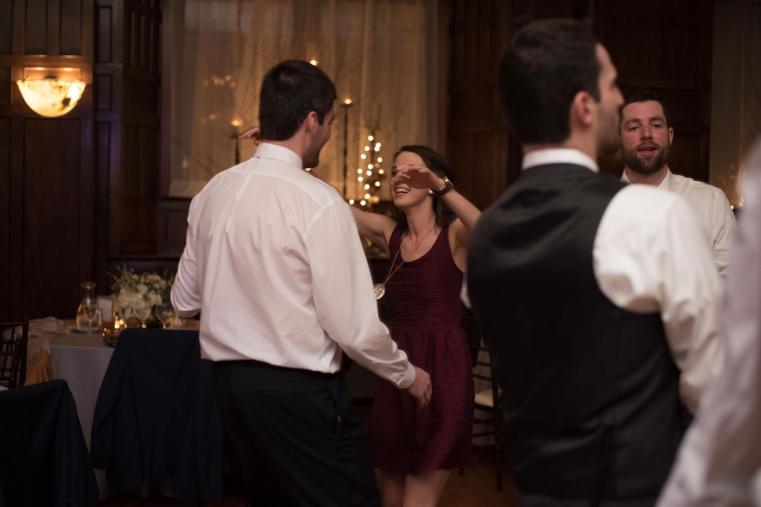 Guests dancing and socializing at an elegant indoor wedding reception in a dimly lit ballroom.