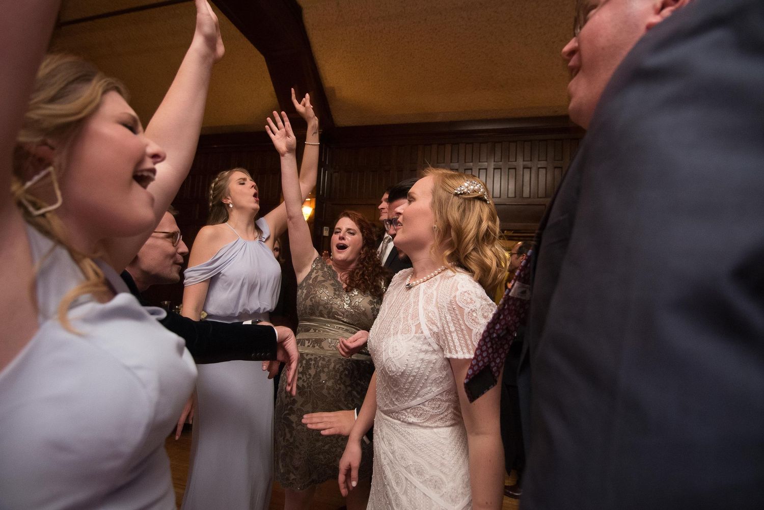 Joyful wedding guests dancing and celebrating together at a lively indoor wedding reception party.