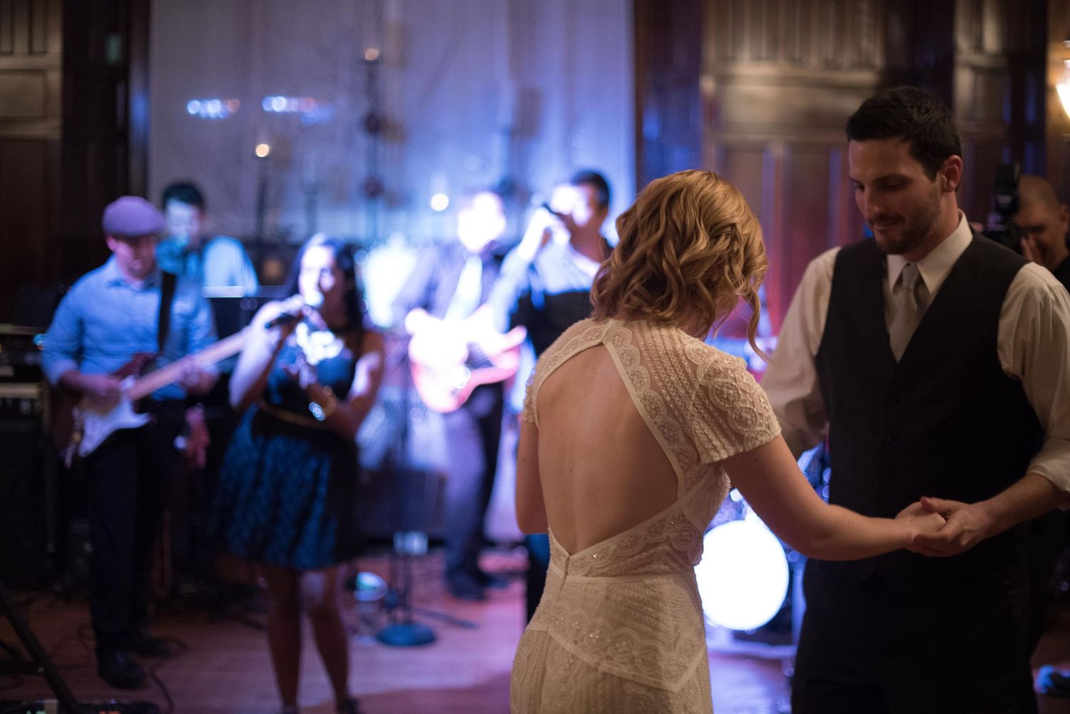 Couple shares first dance at wedding reception with live band performing in background.