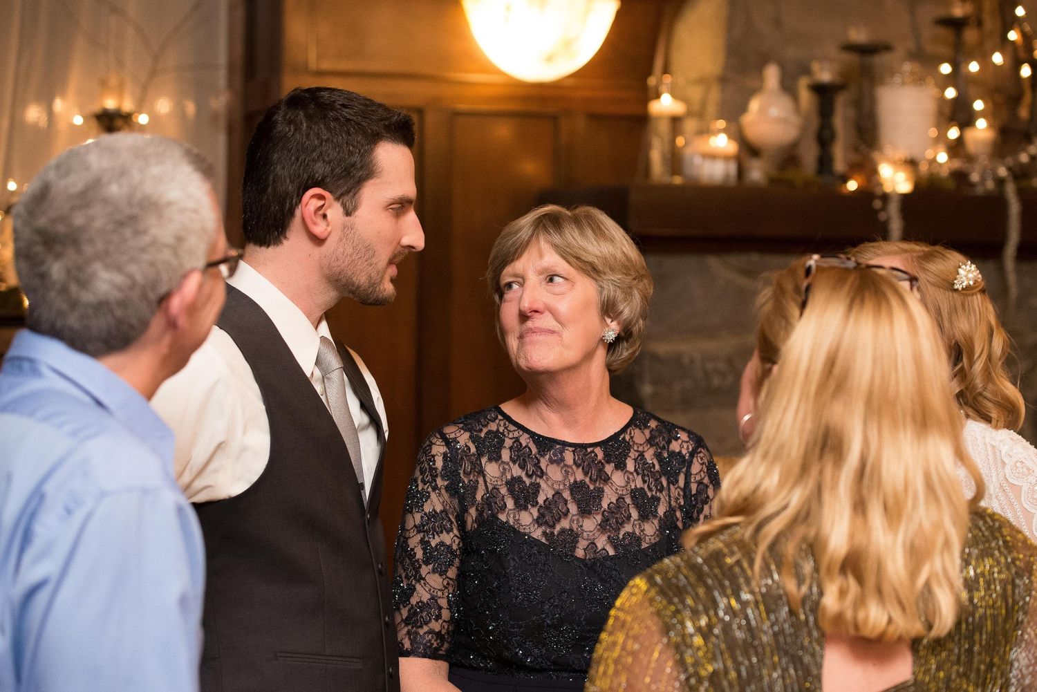 Guests conversing at an elegant indoor wedding reception with warm ambient lighting and decorative backdrop.