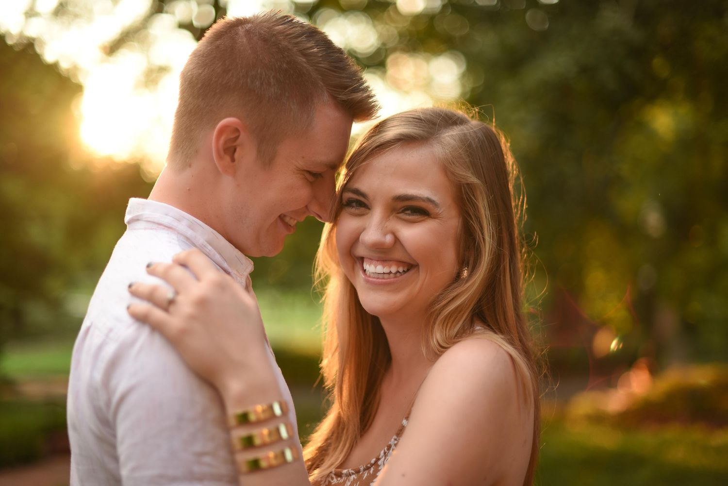 Smiling couple sharing a romantic moment outdoors at golden hour in a park.