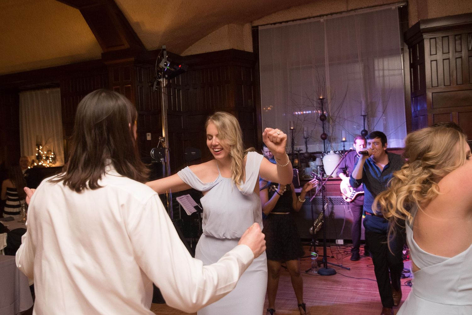 Guests dancing joyfully at an elegant wedding reception with a live band performing in the background.