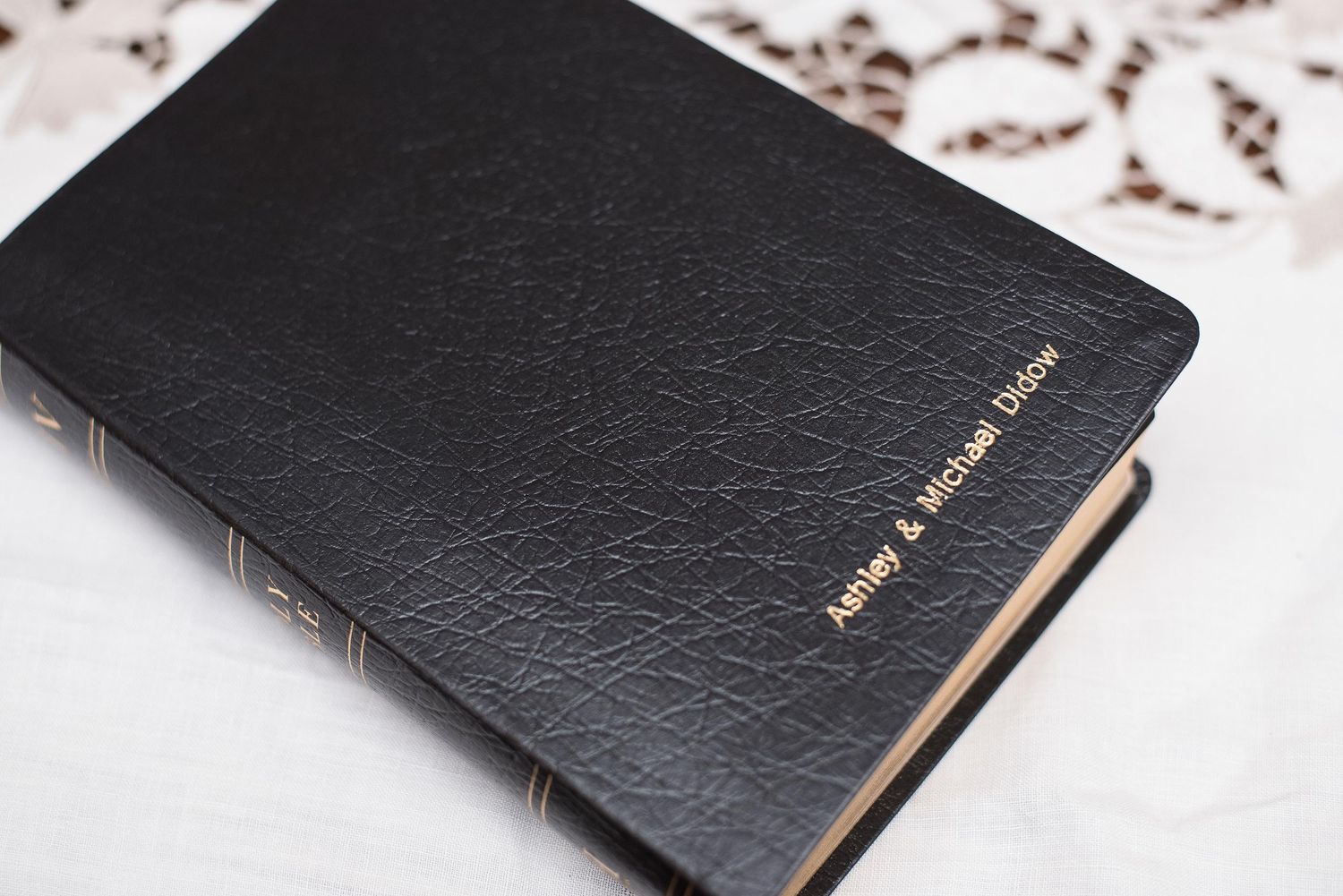 Personalized black leather Bible engraved with names Jeffrey & Michael LaDue on white fabric background.
