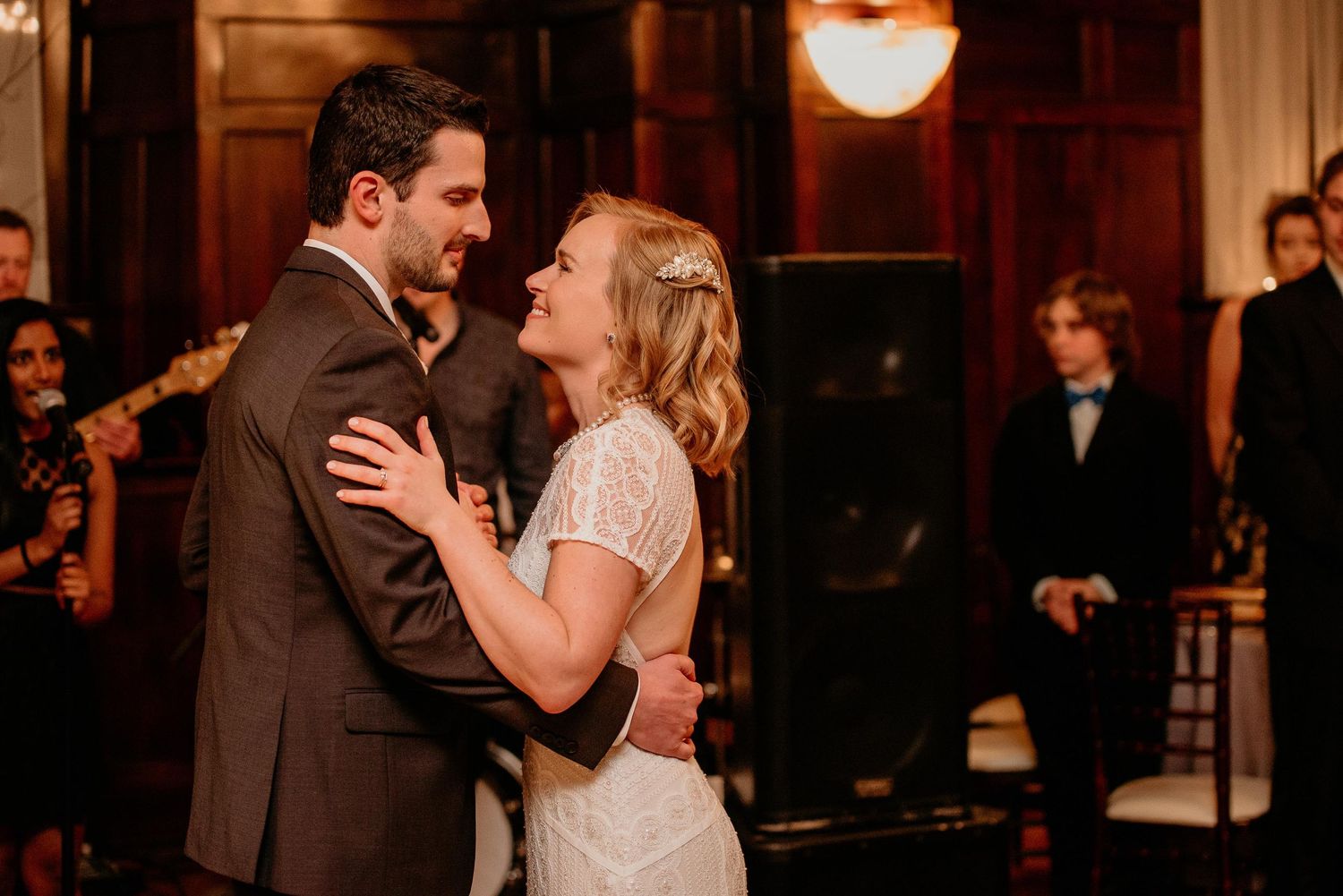 Bride and groom share their first dance at elegant wedding reception with live band performing in background.