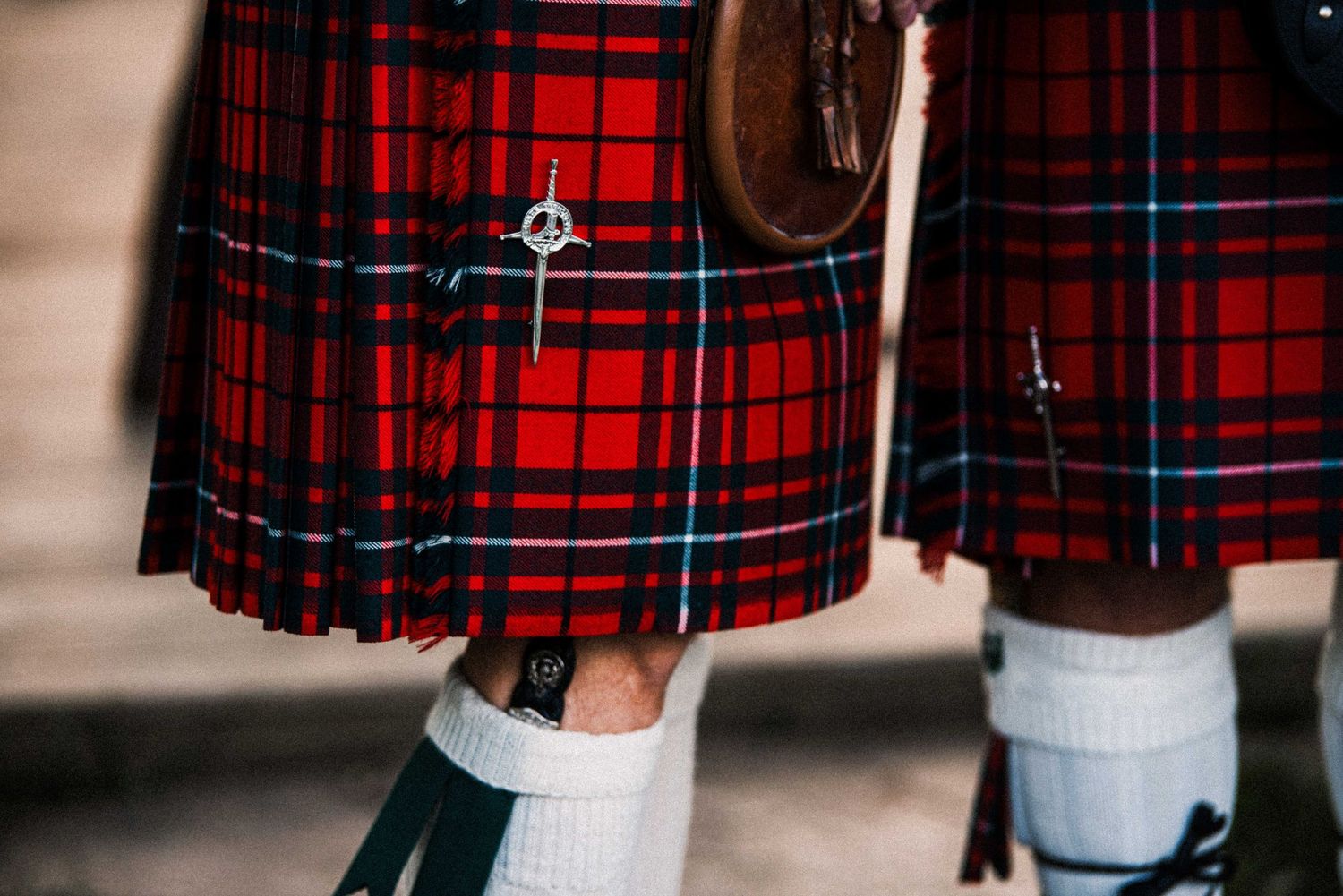 Close-up of a red Royal Stewart tartan kilt with sporran, worn with white socks at a Scottish Highland event.