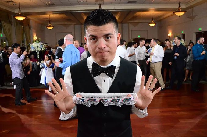 Wedding server in bow tie and vest presenting an empty lace-trimmed tray at a reception.