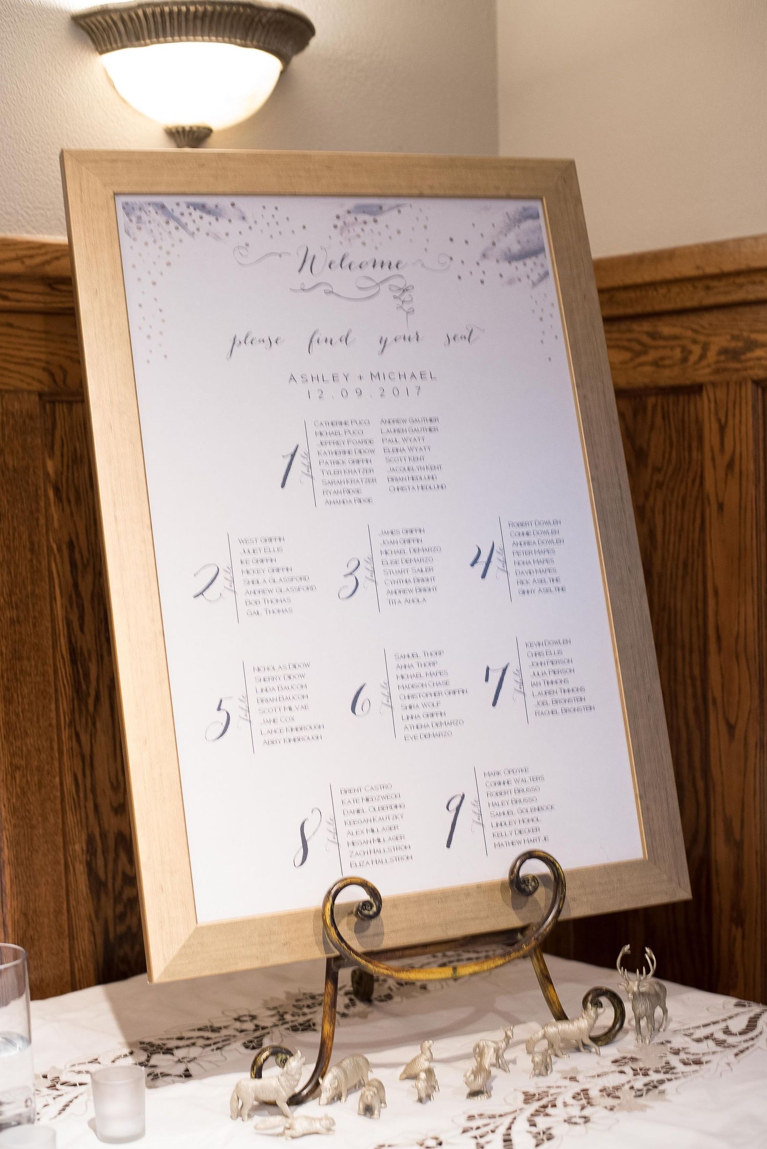 Elegant wedding seating chart in a wooden frame on a decorative easel, welcoming guests to find their seats.