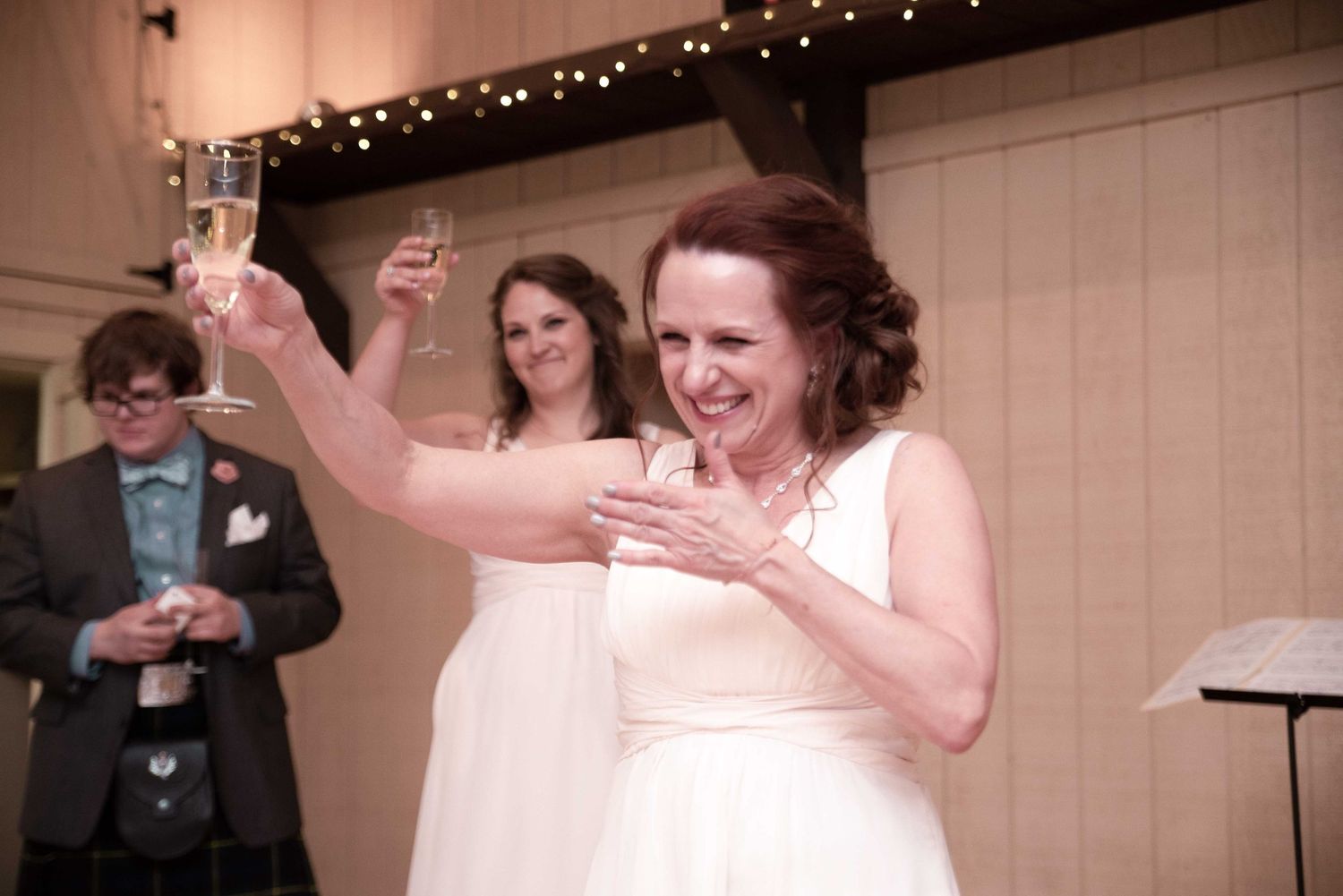 Two brides in white dresses toast with champagne glasses at their wedding reception.