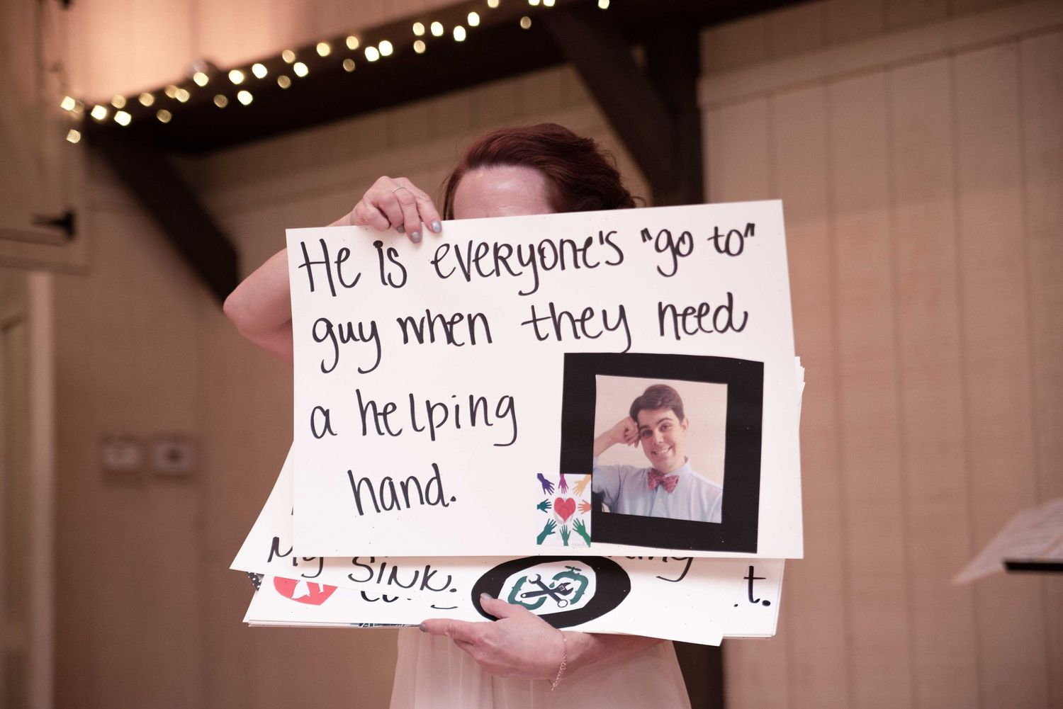 Person holding a handmade sign with a photo reading He is everyone's go to guy when they need a helping hand.