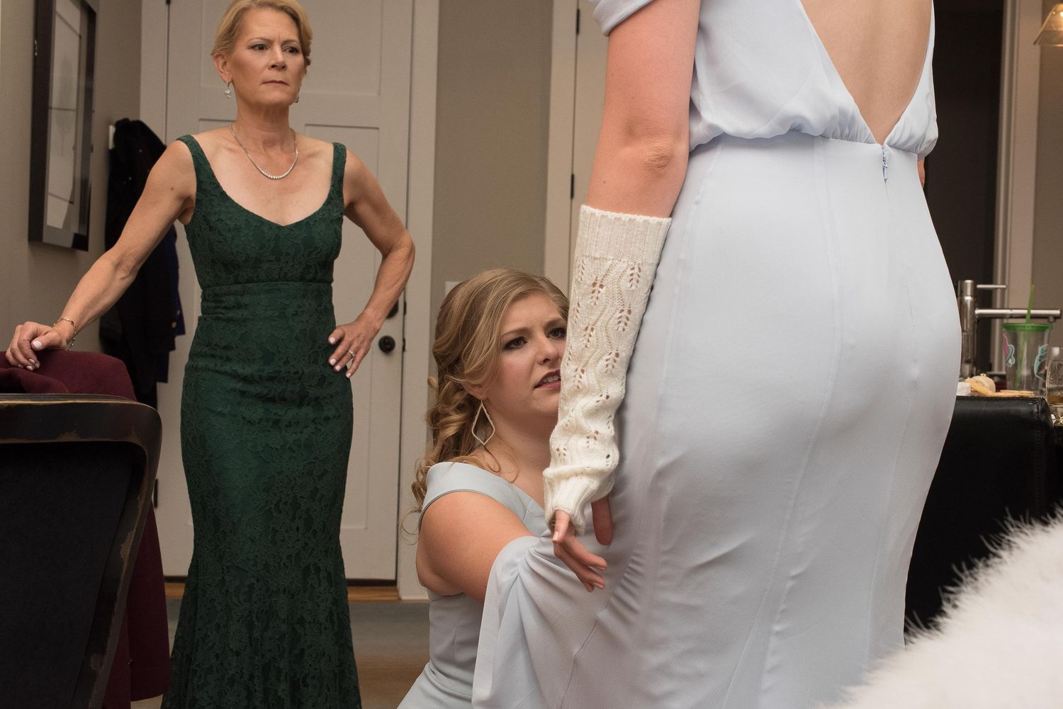 Bridesmaids helping bride with wedding dress fitting in a bridal suite.