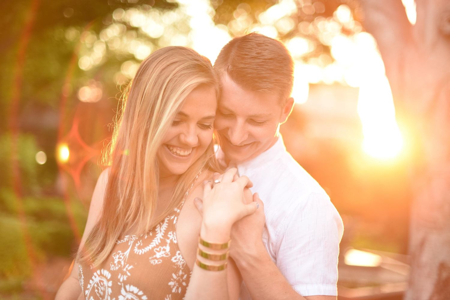 Happy couple sharing a tender moment bathed in warm golden sunset light outdoors.