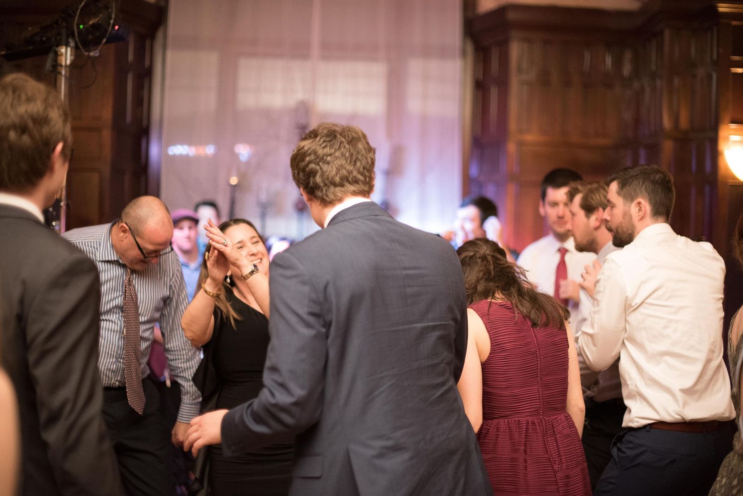 Guests dancing and socializing at an elegant indoor wedding reception in a warmly lit venue.