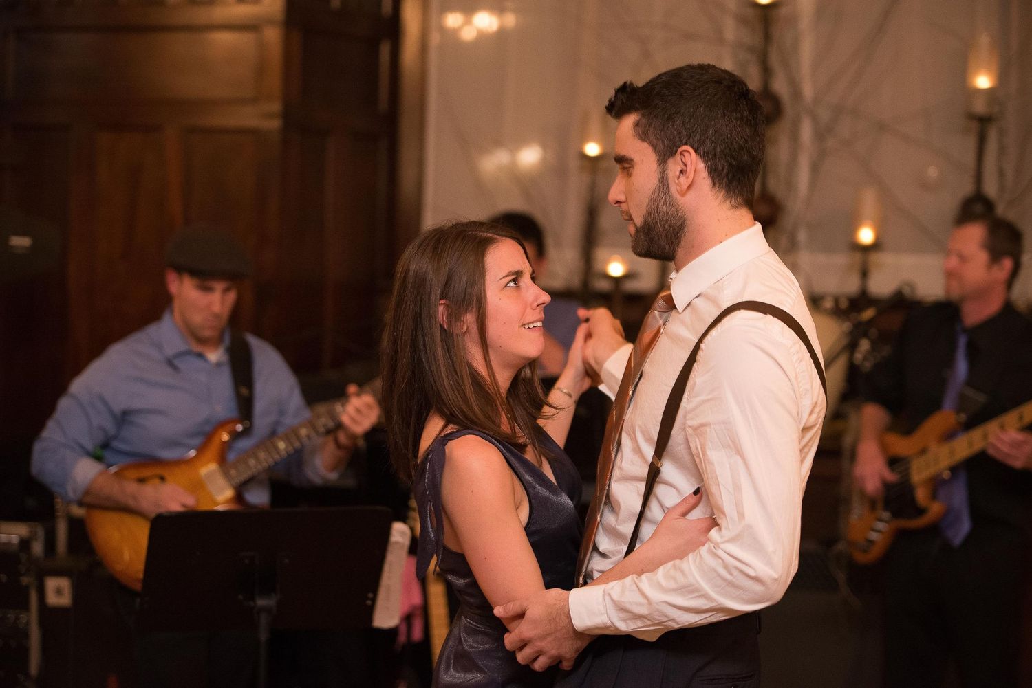 Couple shares romantic dance at wedding reception with live band performing in background.