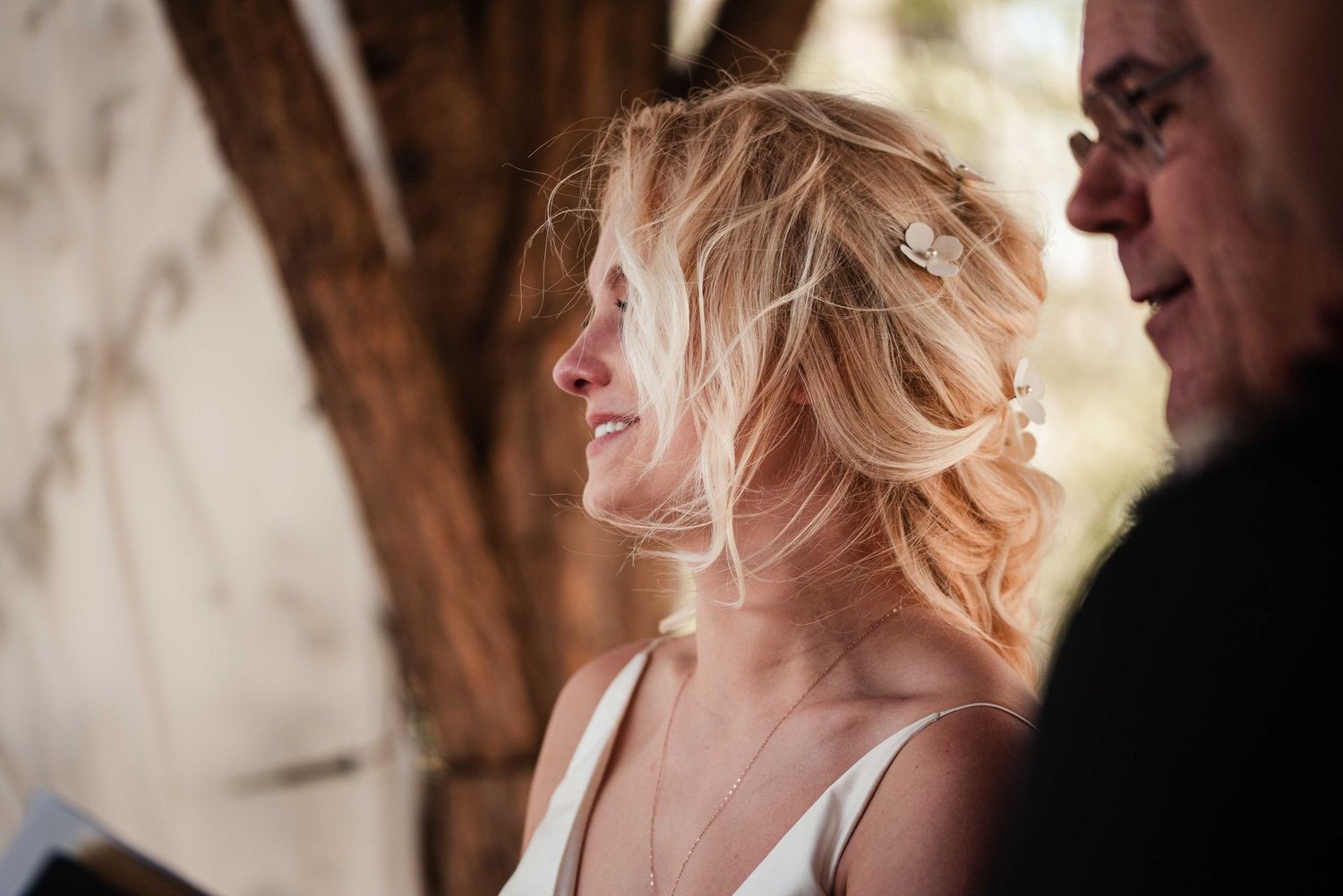 Smiling blonde bride with hair accessories during outdoor wedding ceremony.