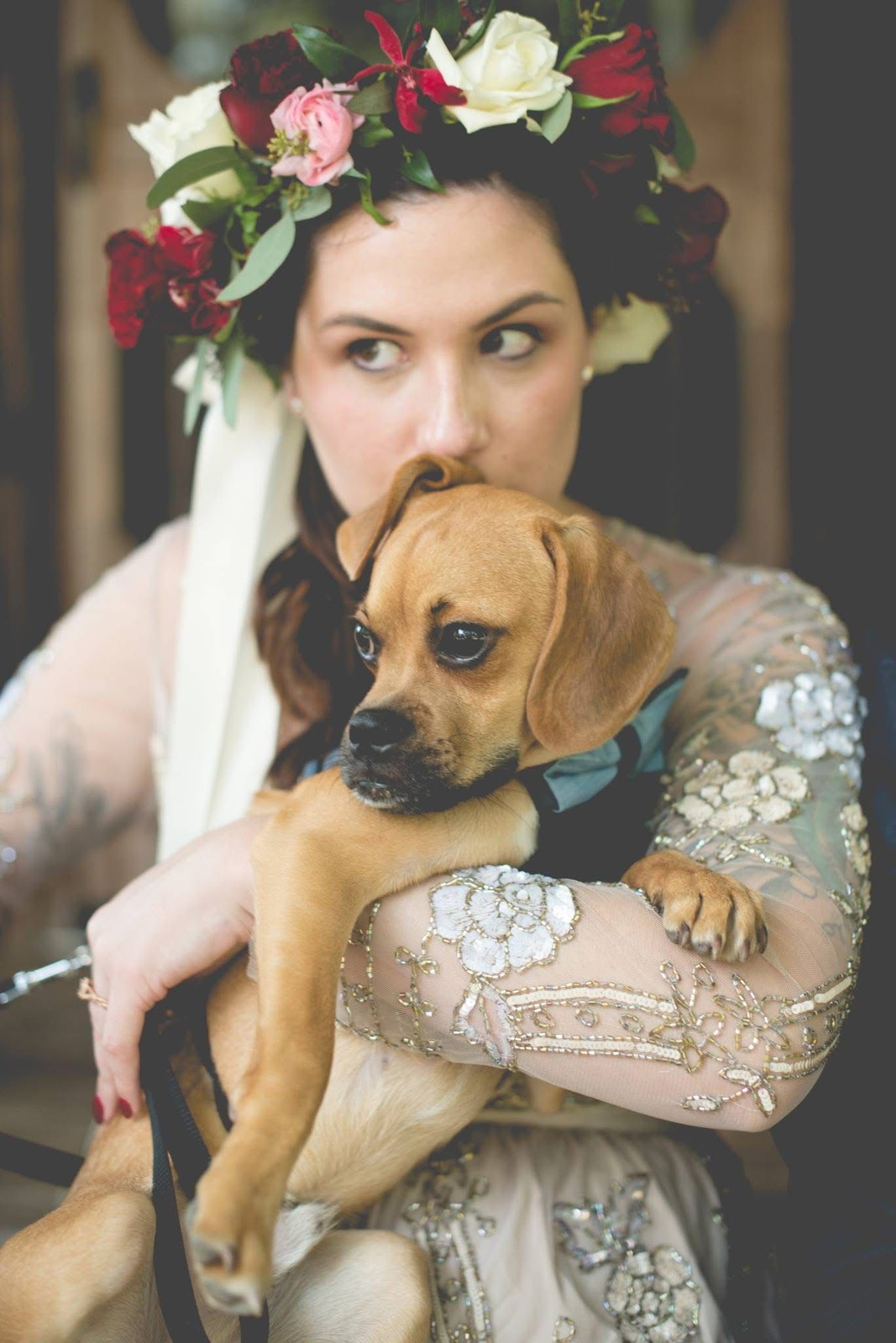 Bohemian bride wearing floral crown holding an adorable small brown puppy.