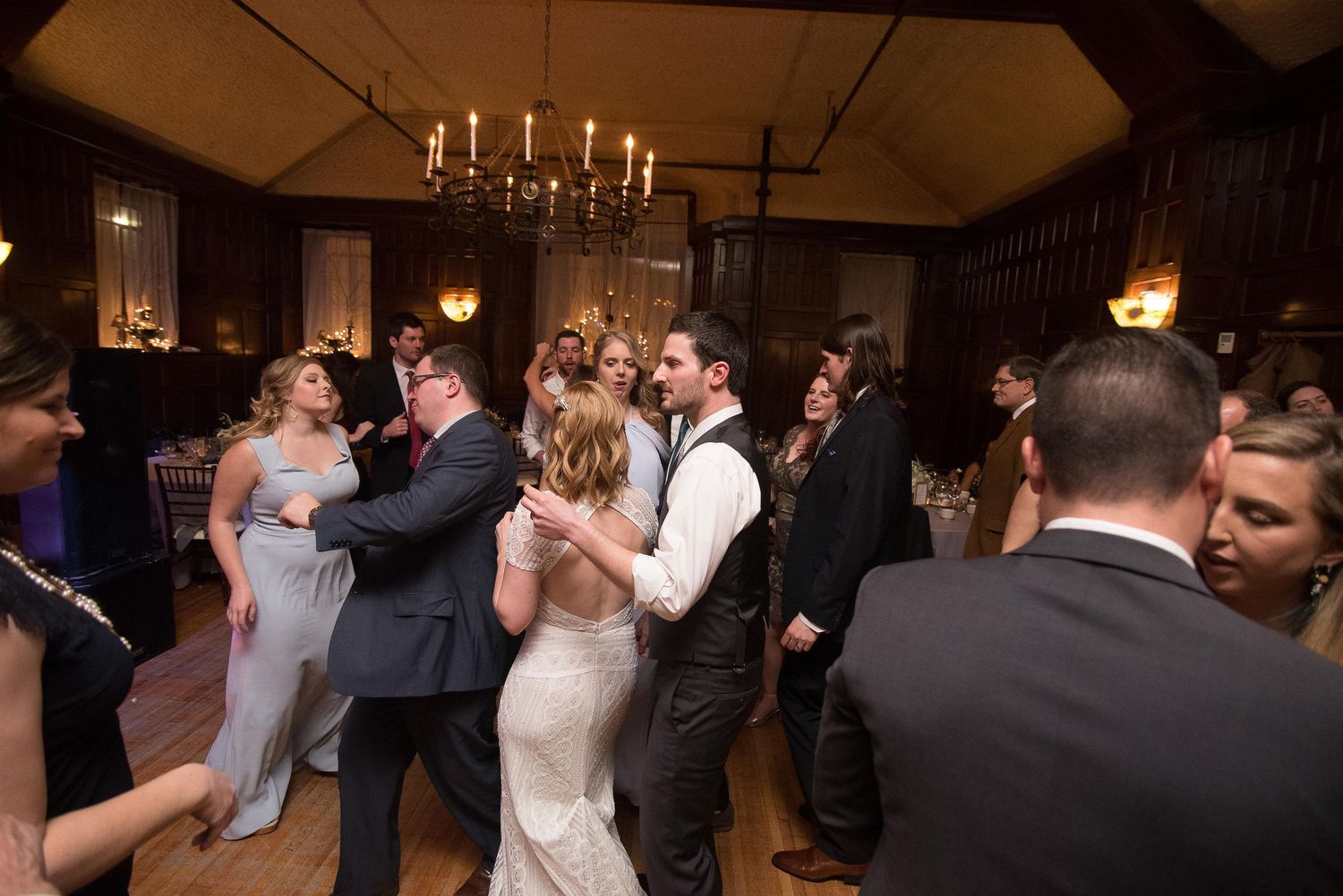 Bride and groom share first dance surrounded by guests in elegant candlelit wedding reception venue.