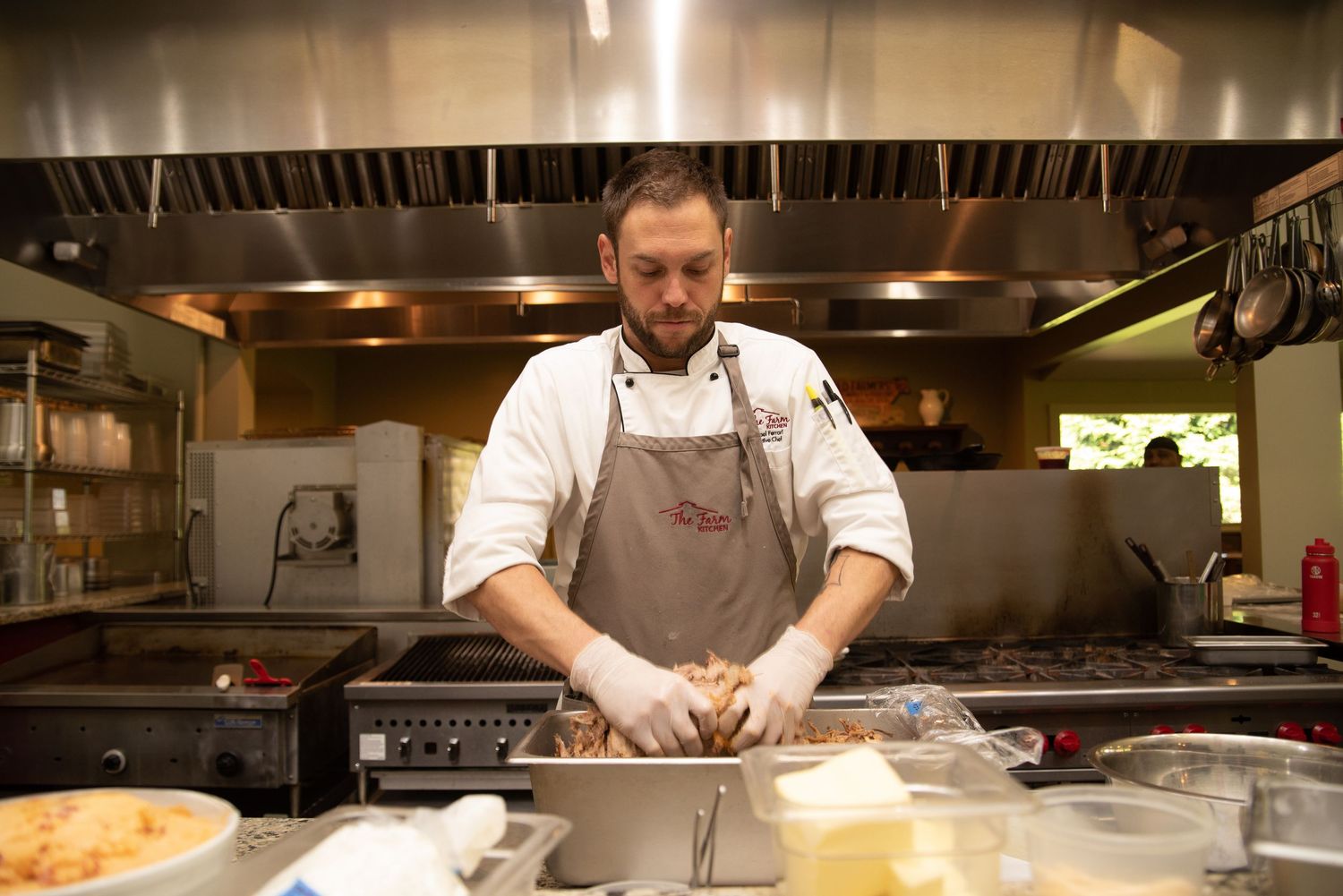 Professional chef in white apron prepares food in commercial kitchen for wedding catering.