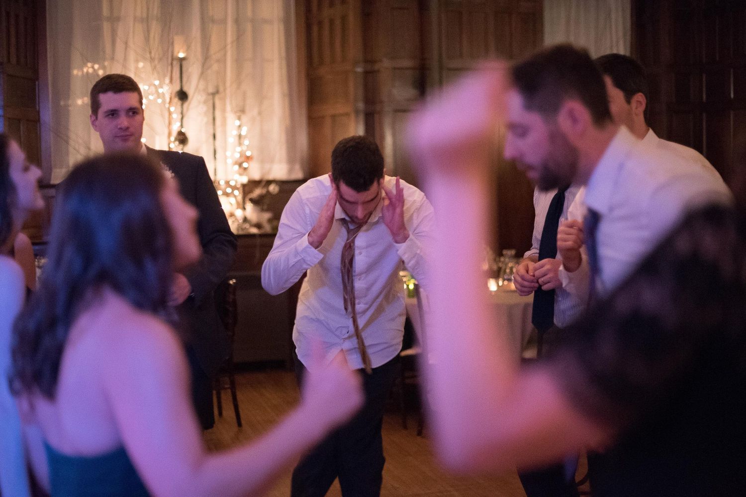 Guests dancing and celebrating at an elegant wedding reception in a warmly lit venue.