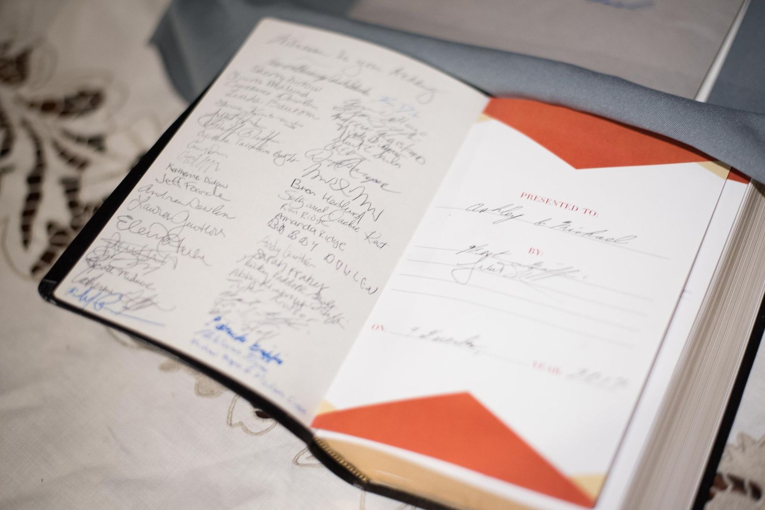 Open guest book with signatures on left page and handwritten dedication on right page with orange bookmark.