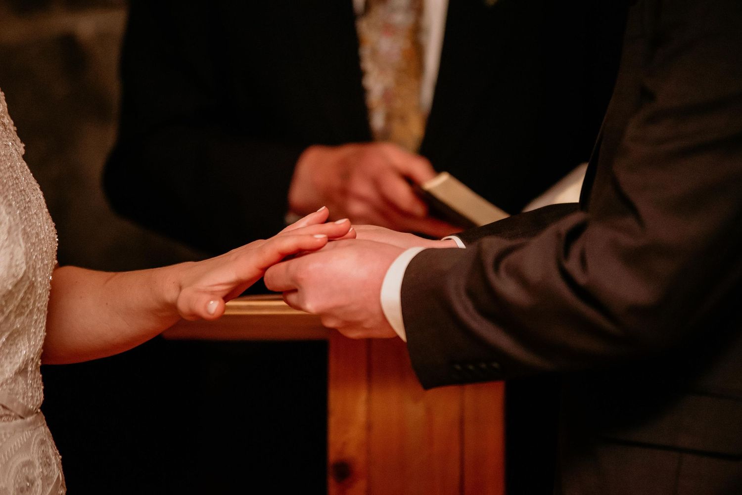 Close-up of couple exchanging rings at wedding altar during ring ceremony.
