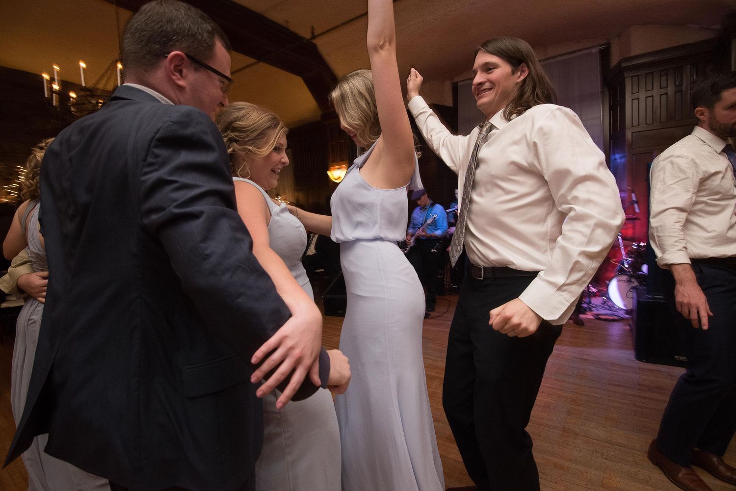 Guests dancing joyfully at a wedding reception in an elegant venue with warm lighting.