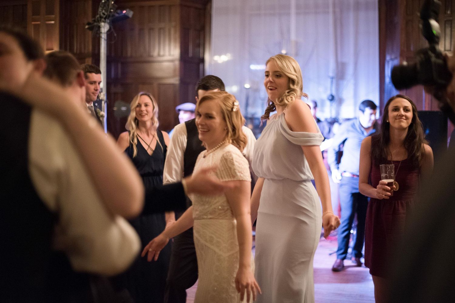 Guests dancing and celebrating at an elegant wedding reception in a grand wooden ballroom.