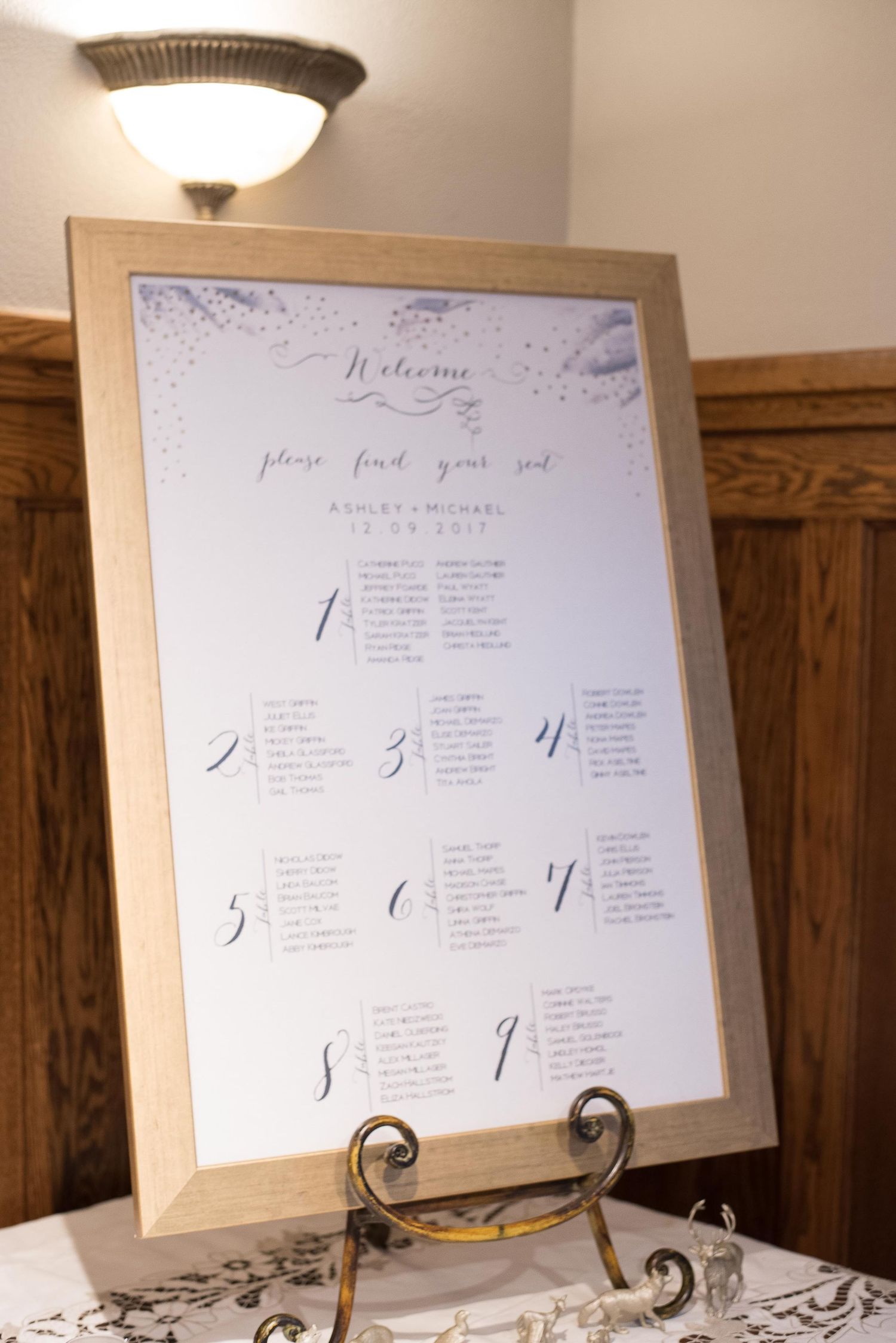 Elegant wedding seating chart in gold frame displaying table assignments for Ashley and Michael's reception.