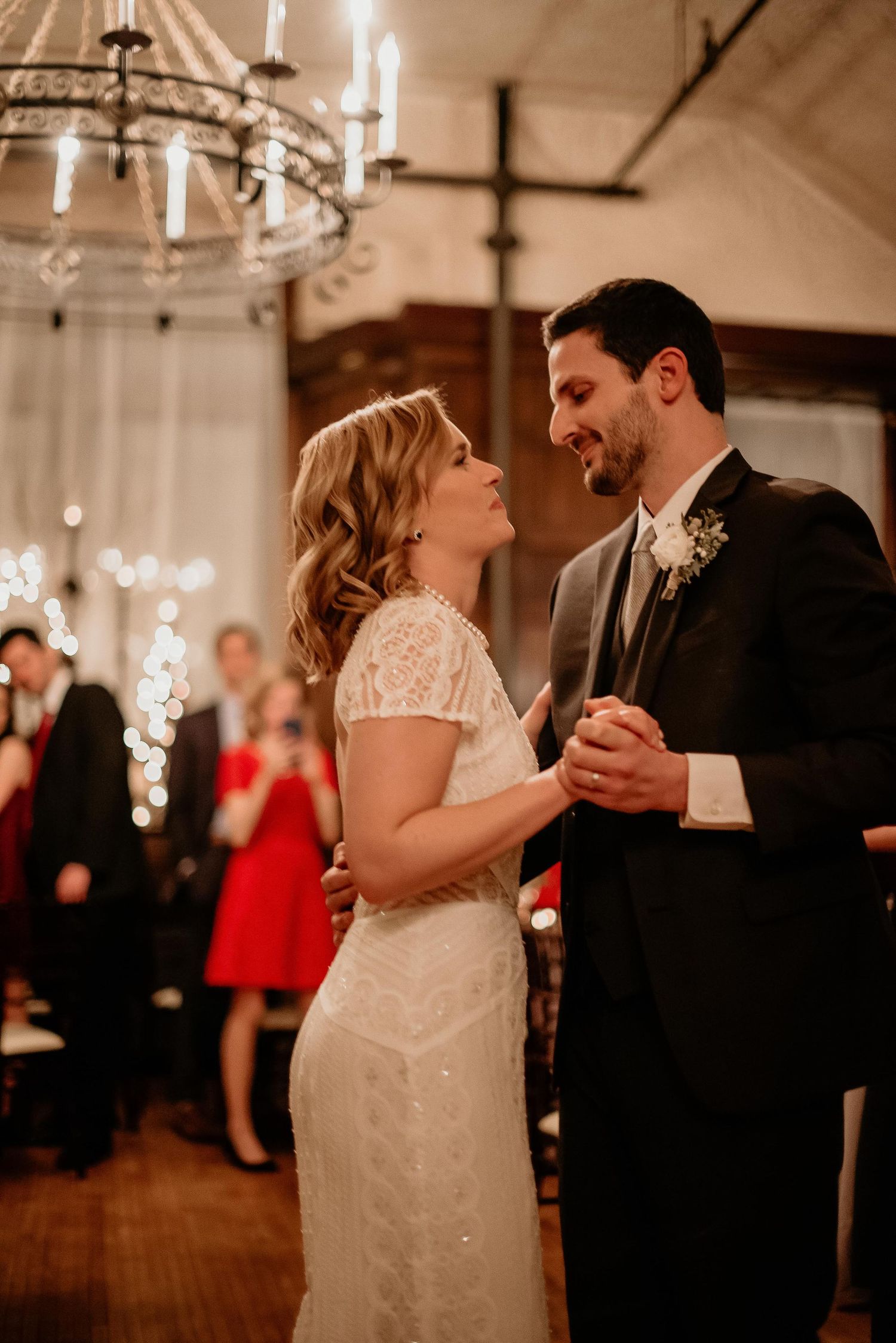 Bride and groom share their first dance under a chandelier at an elegant wedding reception.