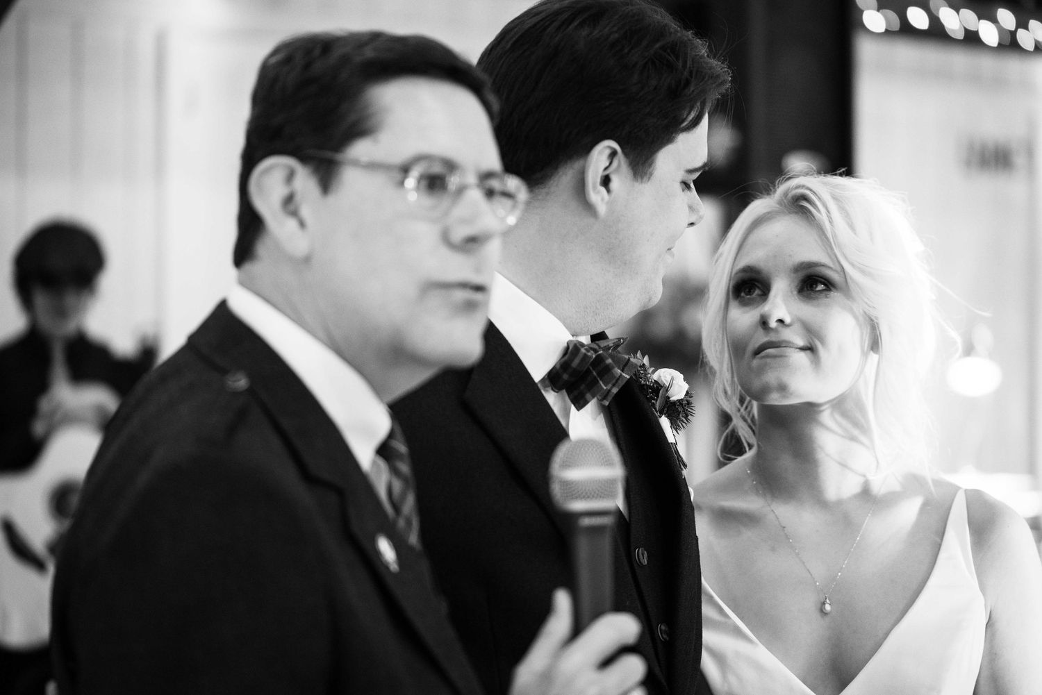 Black and white wedding ceremony photo with bride, groom, and officiant at the altar.