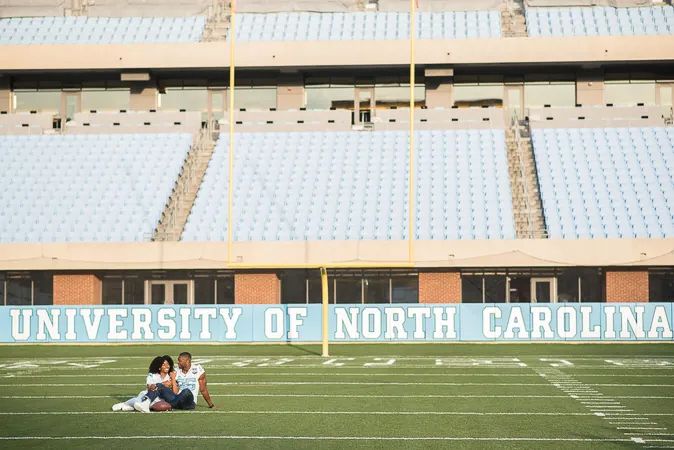 Couple relaxing together on University of North Carolina football field turf near the end zone.