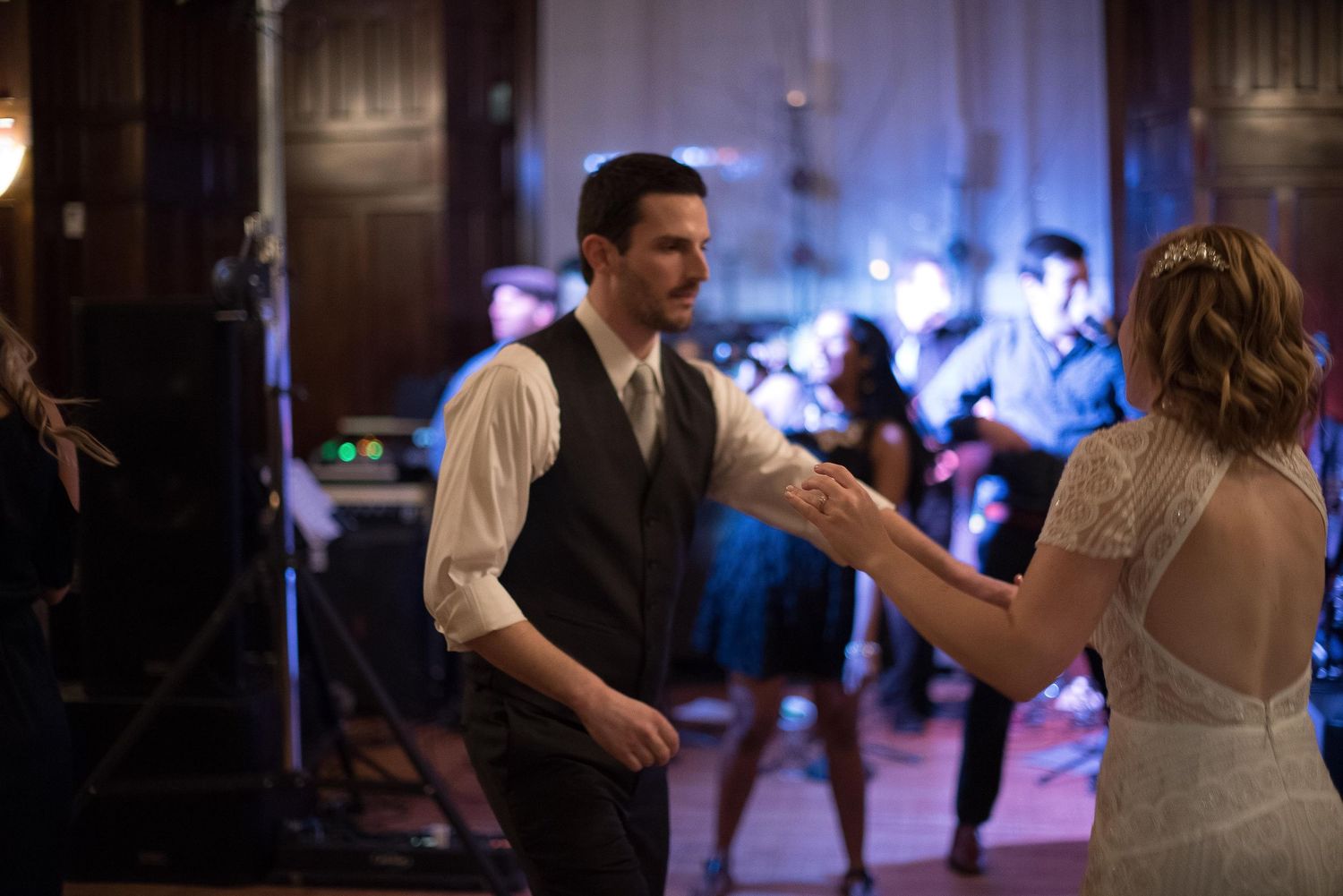 Couple sharing first dance at wedding reception with live band performing in background.