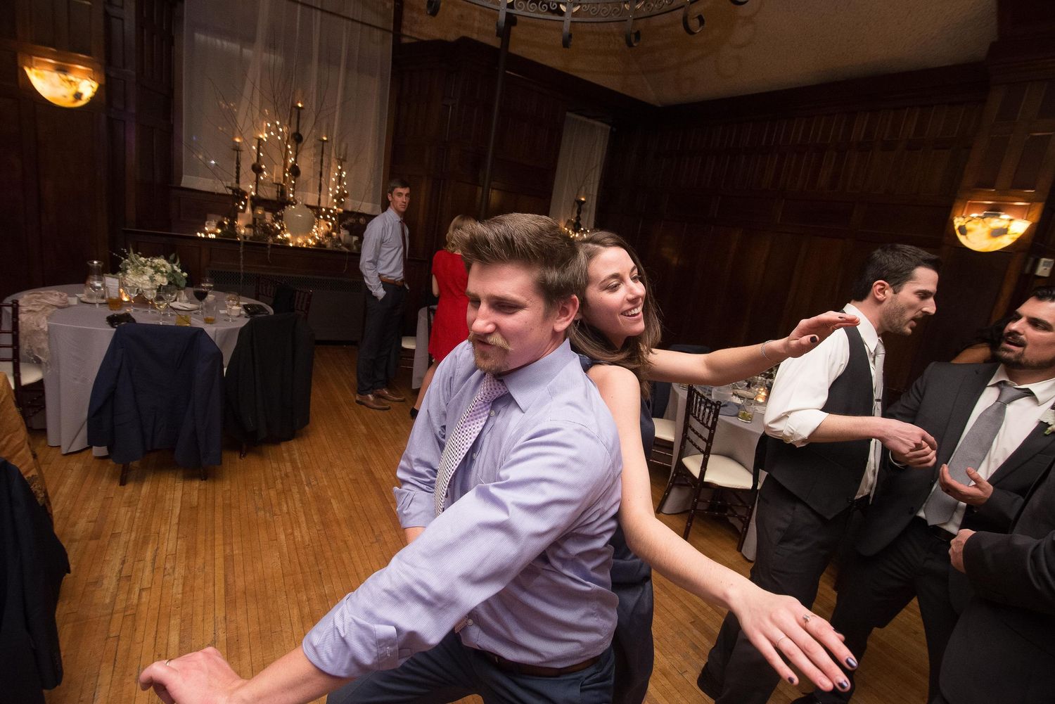 Guests dancing energetically at an elegant wedding reception in a warmly lit ballroom venue.