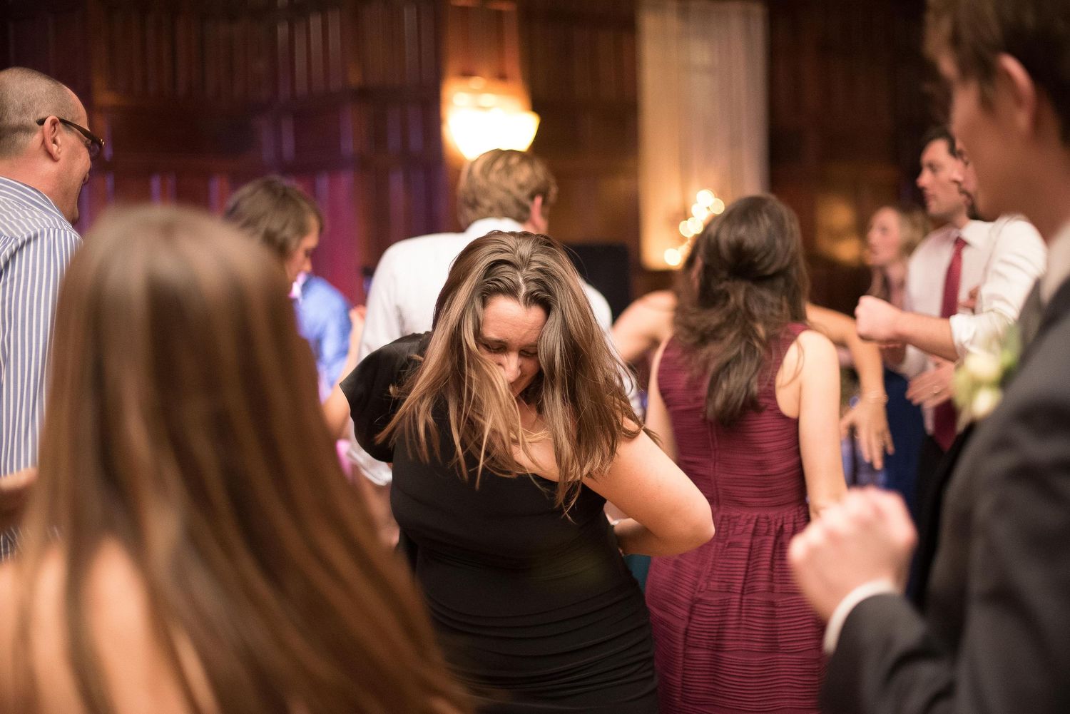 Guests dancing energetically at a wedding reception in an elegant venue with warm lighting.