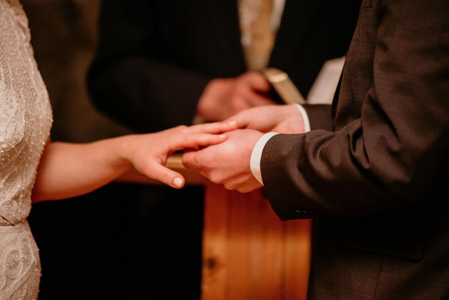 Close-up of a groom placing a wedding ring on the bride's finger during a wedding ceremony.