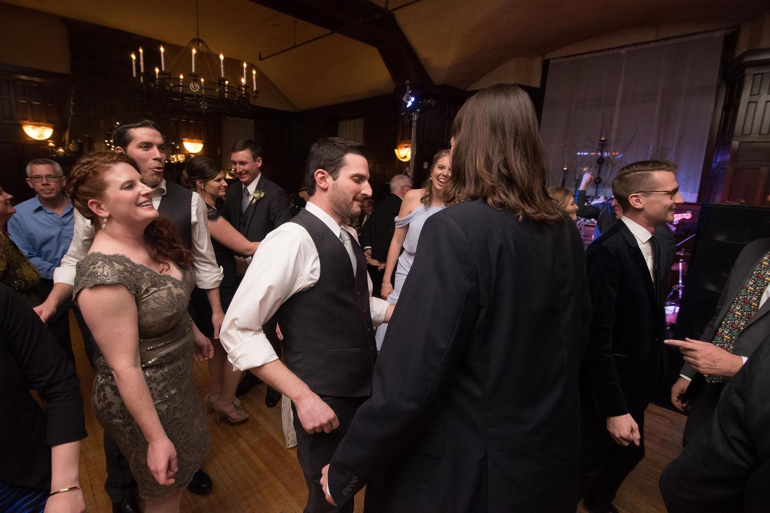 Guests dancing and celebrating at an elegant wedding reception in a warmly lit ballroom venue.