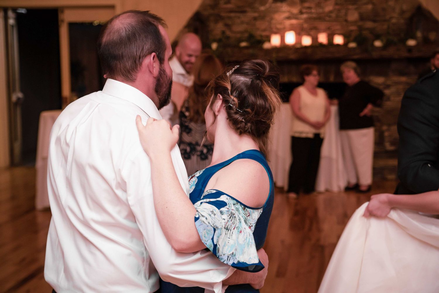 Couples dancing at a wedding reception in a rustic stone venue with warm lighting.