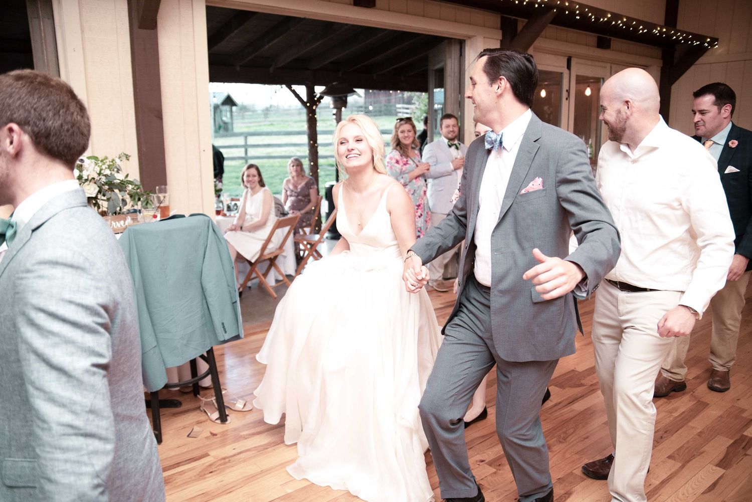 Bride in white gown dancing with groom in gray suit at elegant indoor wedding reception celebration.