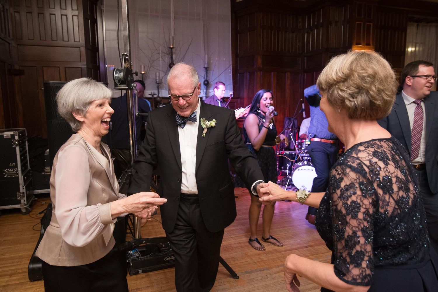 Elegantly dressed guests dancing and socializing at a formal gala event with a live band performing in the background.
