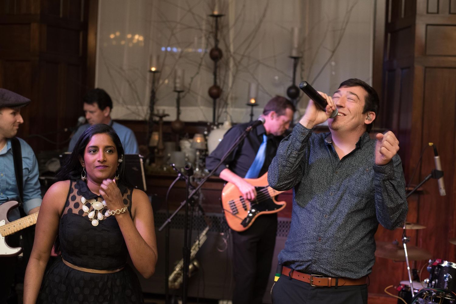 Live band performing at elegant venue with male vocalist singing and female singer dancing on stage.