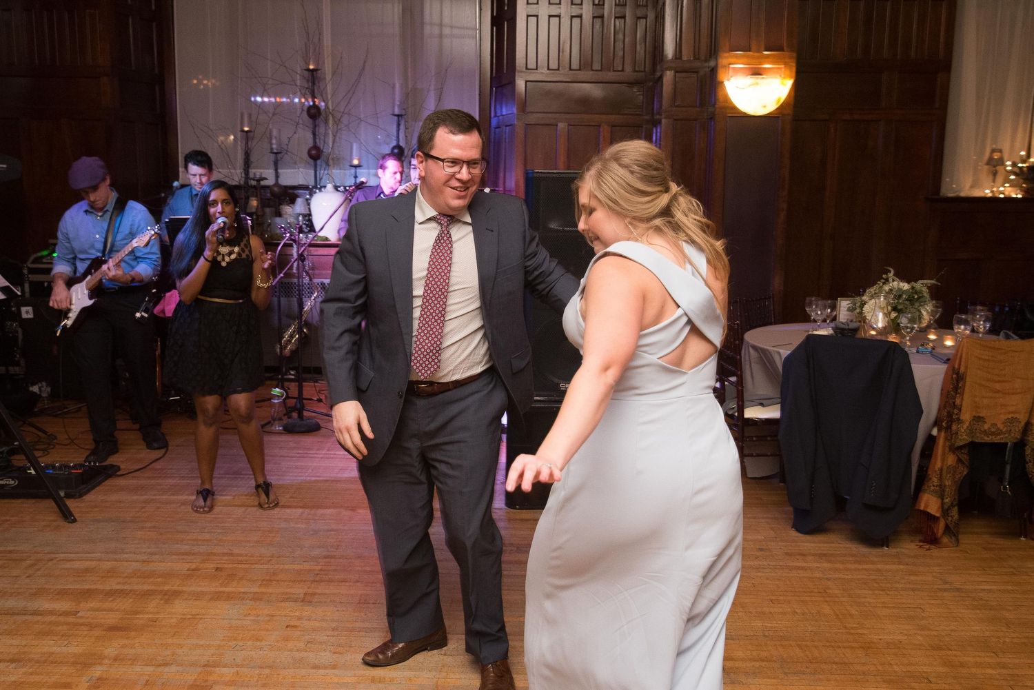 Couple dancing at wedding reception with live band performing in elegant ballroom venue.
