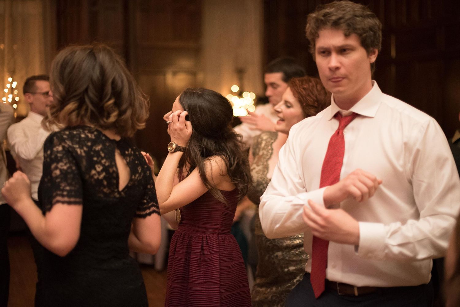 Elegantly dressed couples dancing at a formal event, man in white shirt and red tie in foreground.