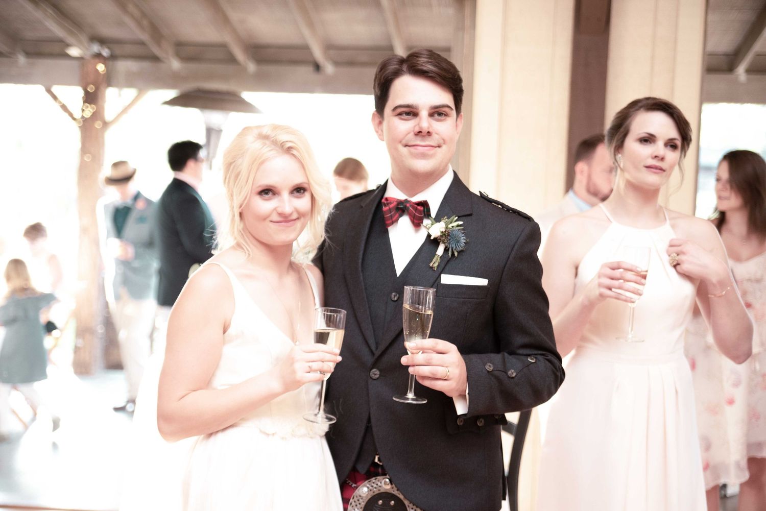 Bride and groom smiling and holding champagne glasses at their wedding reception.