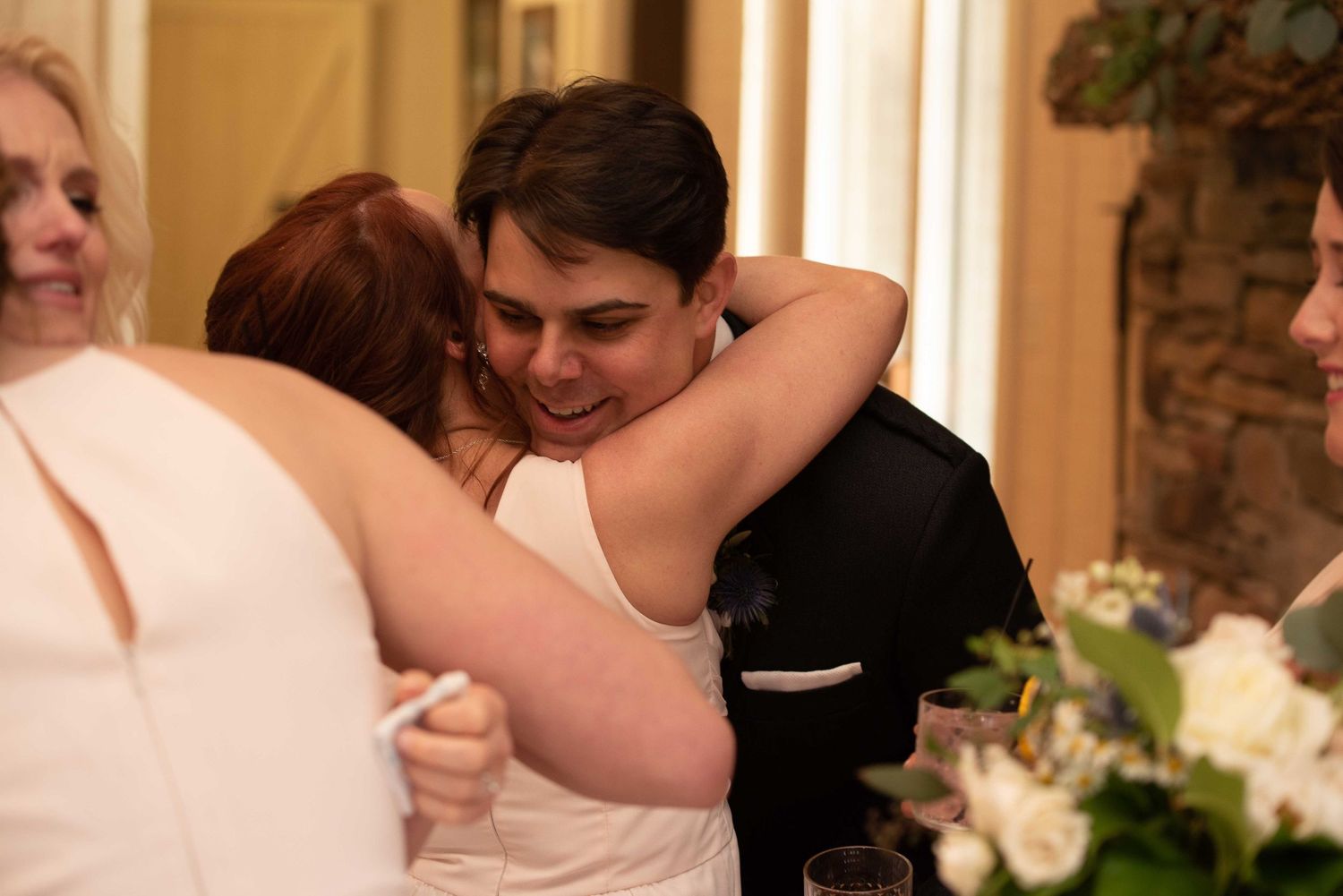 Groom hugging a guest in a white dress at an elegant wedding reception venue.