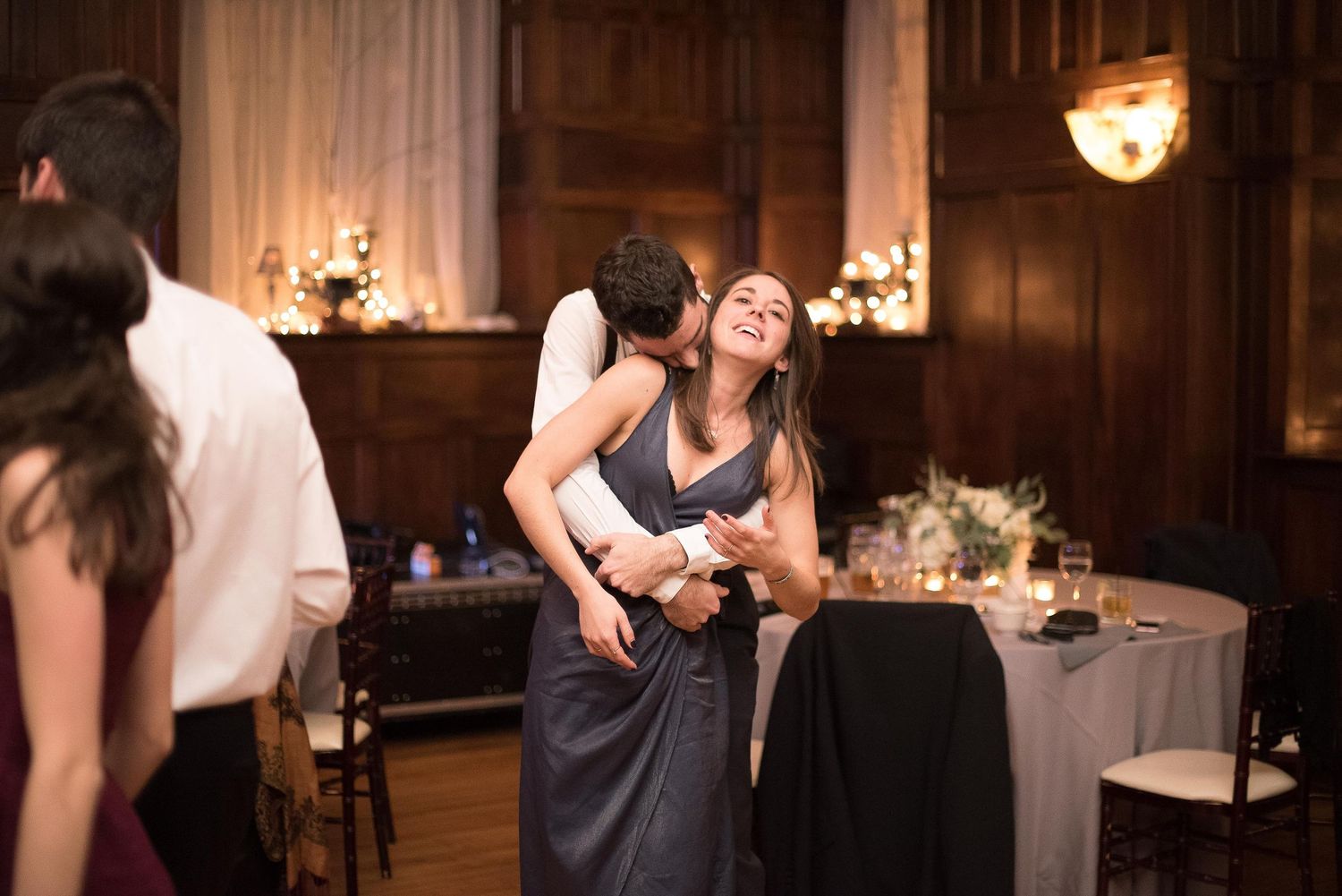 Couple sharing a romantic dance embrace at an elegant candlelit wedding reception venue.