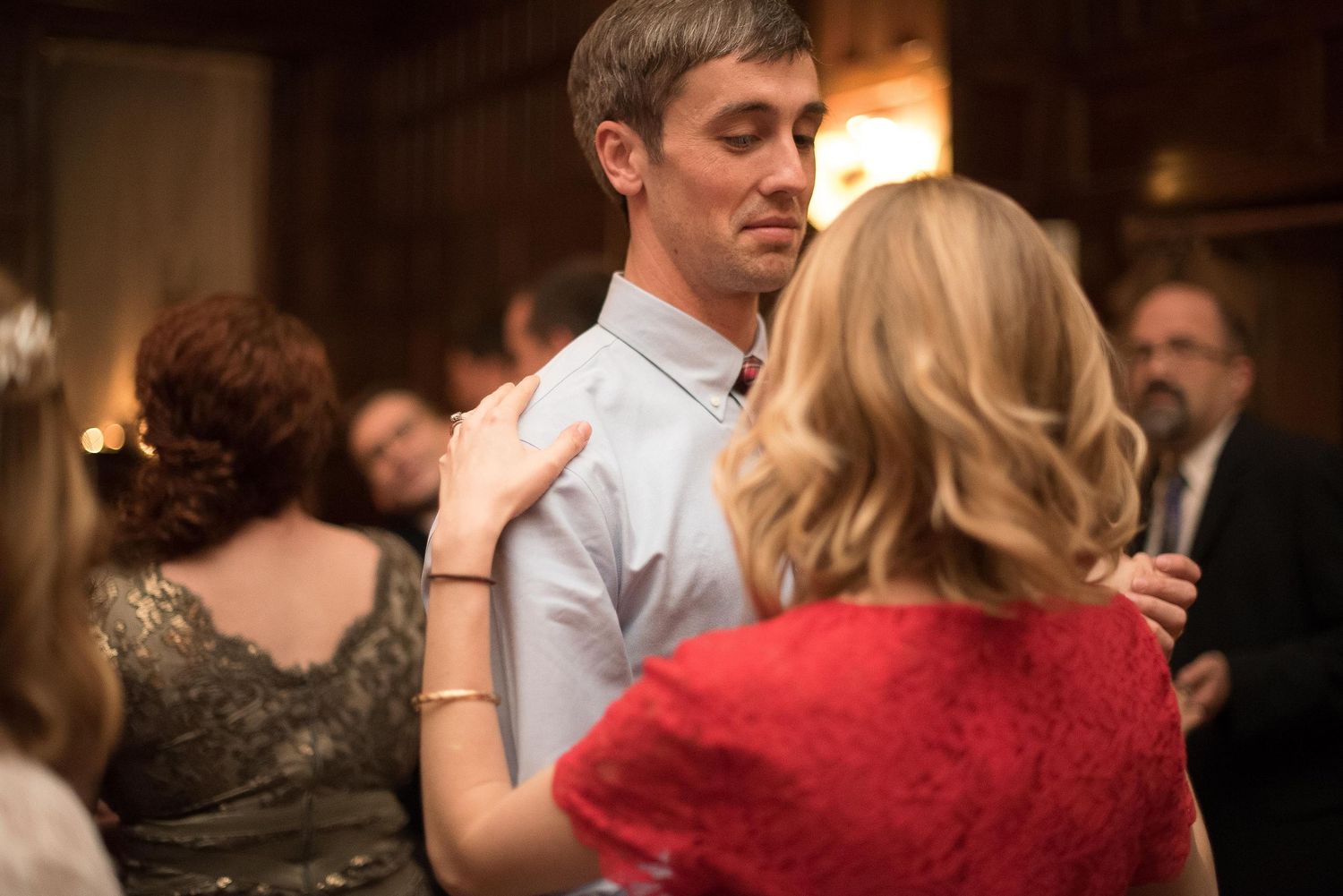 Couple slow dancing at formal indoor event in dimly lit venue.