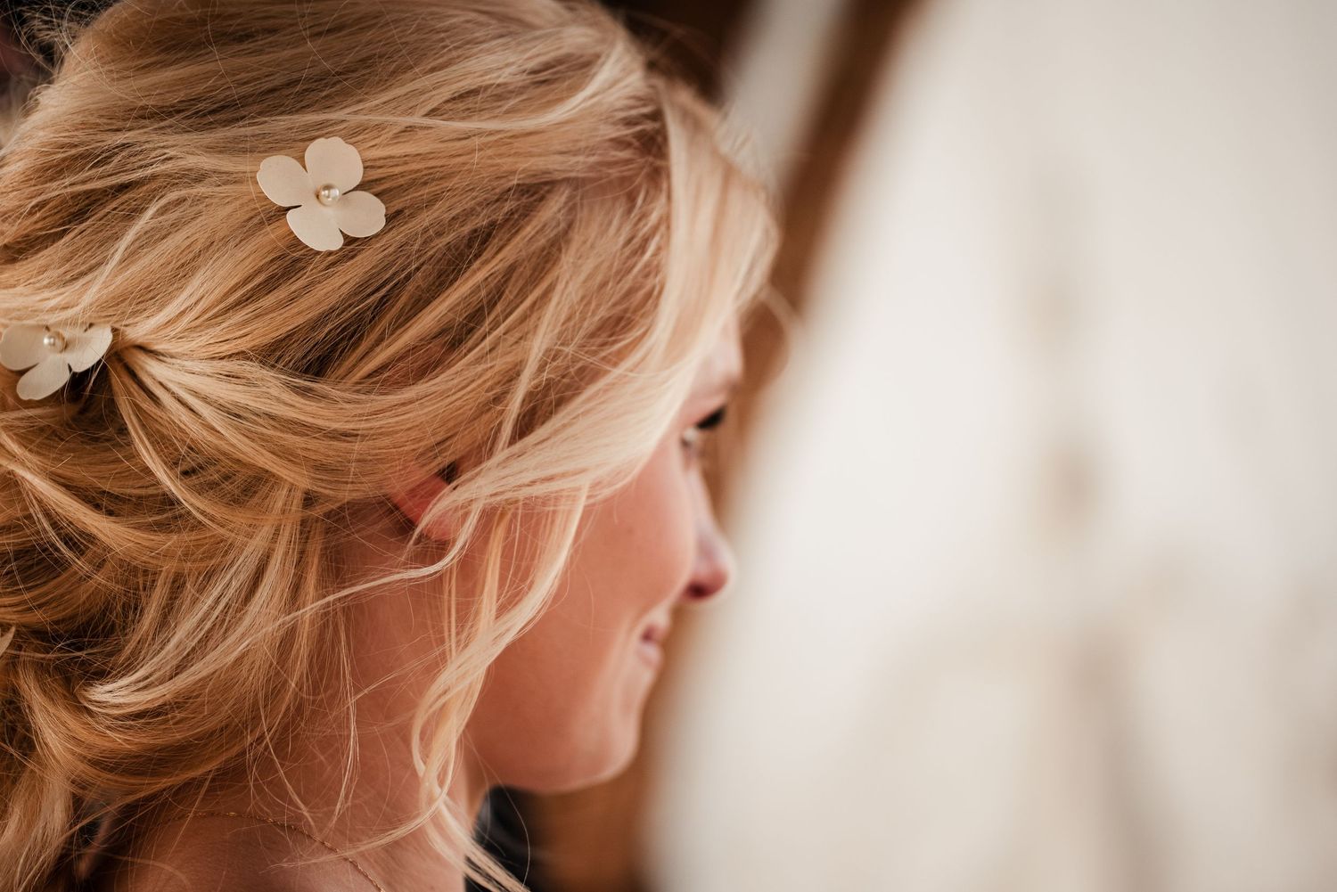 Close-up of blonde bride with floral hair pins in elegant updo hairstyle for wedding day.