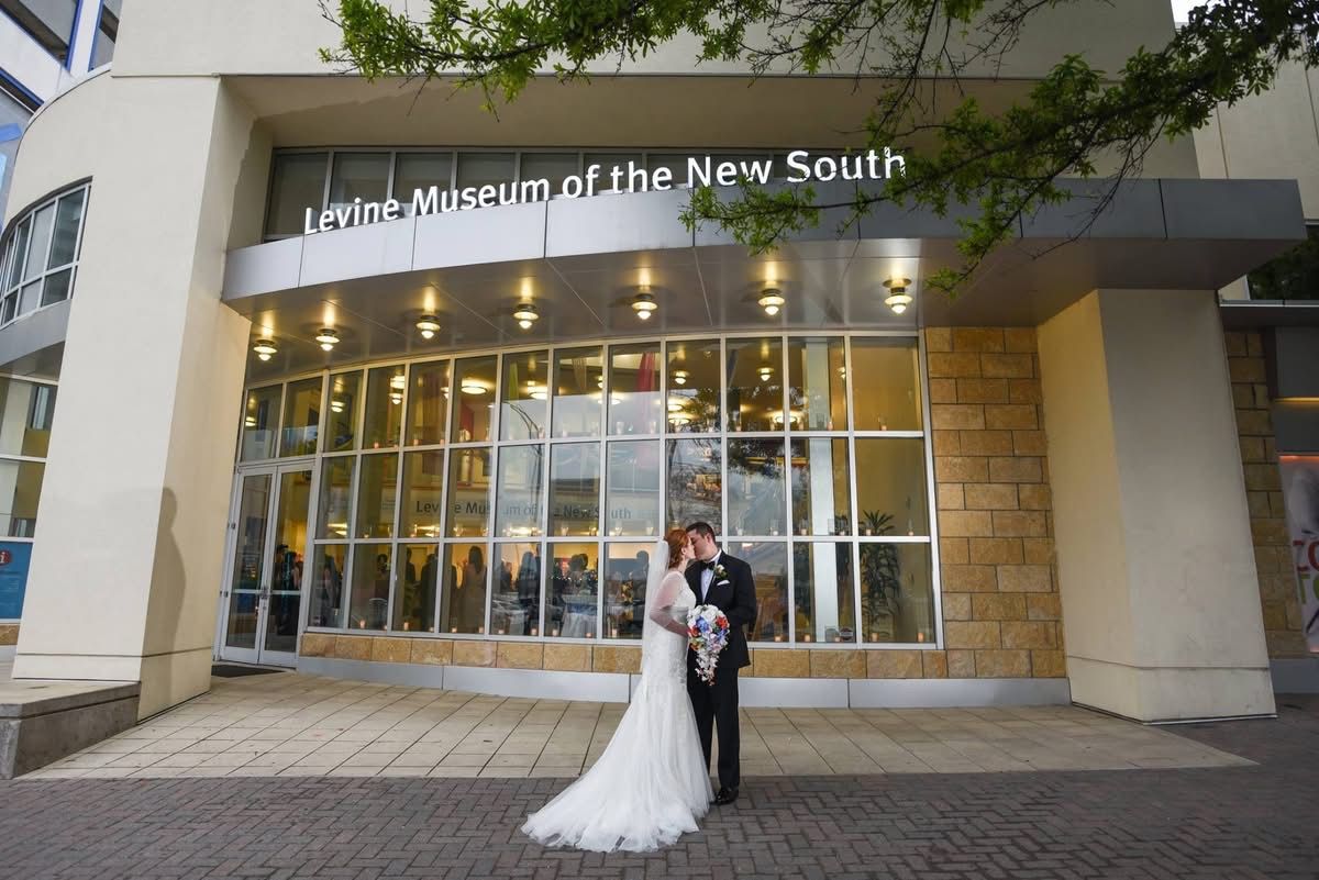 Bride and groom kissing outside the Levine Museum of the New South in Charlotte.